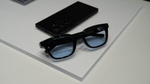 黒いスマートグラスとスマートフォンが白いテーブルに置かれている展示風景